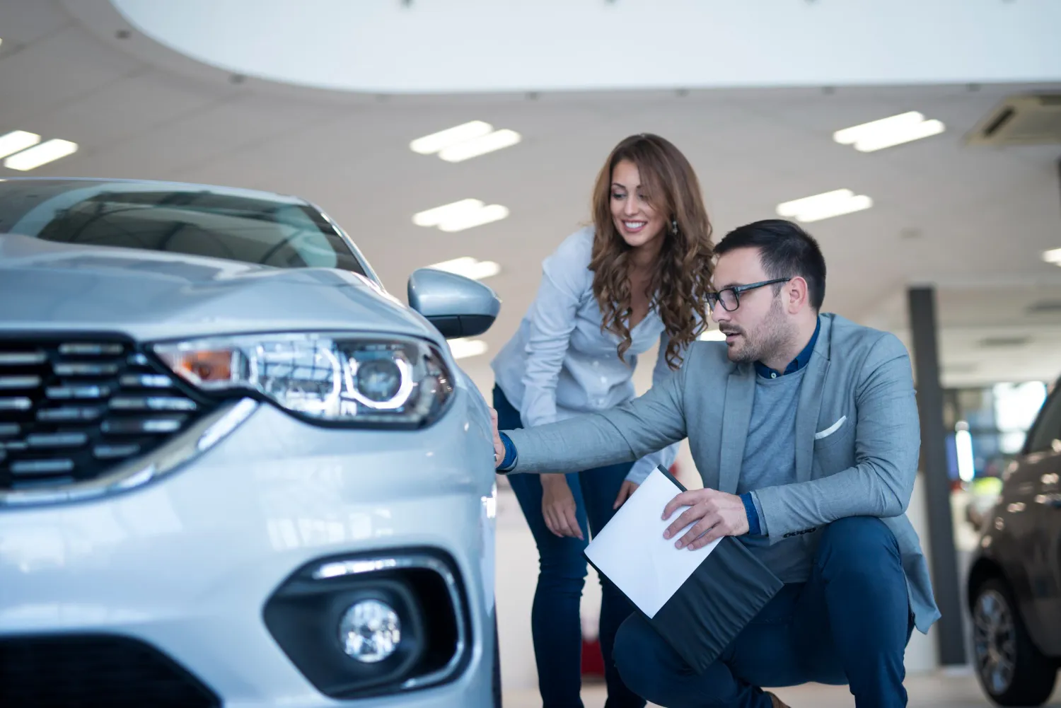 People in car dealership showroom discussing about new vehicle<br />